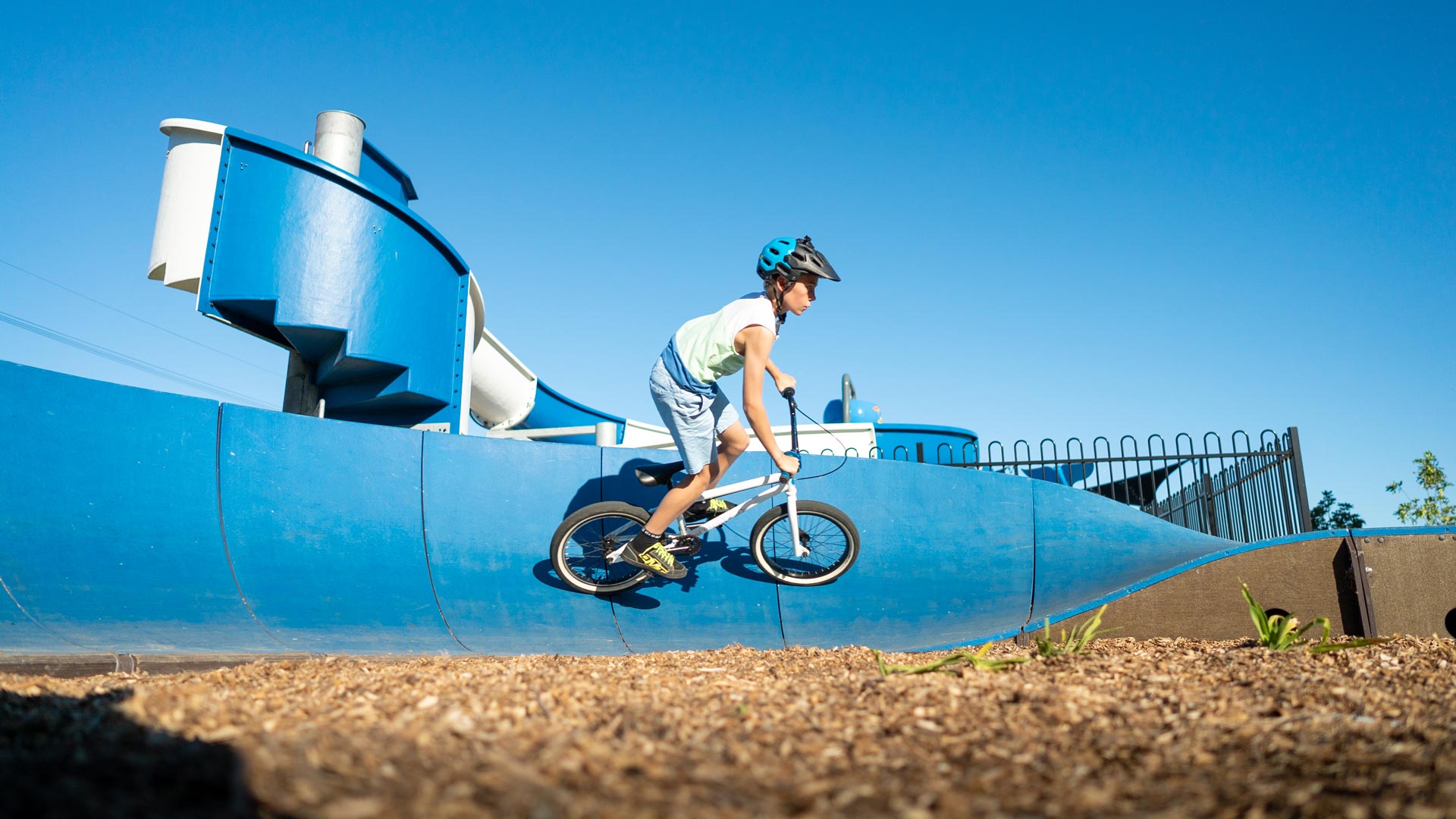 Boy riding BMX on Parkitect Blue Plywood Composite Pump Track at Holiday Park